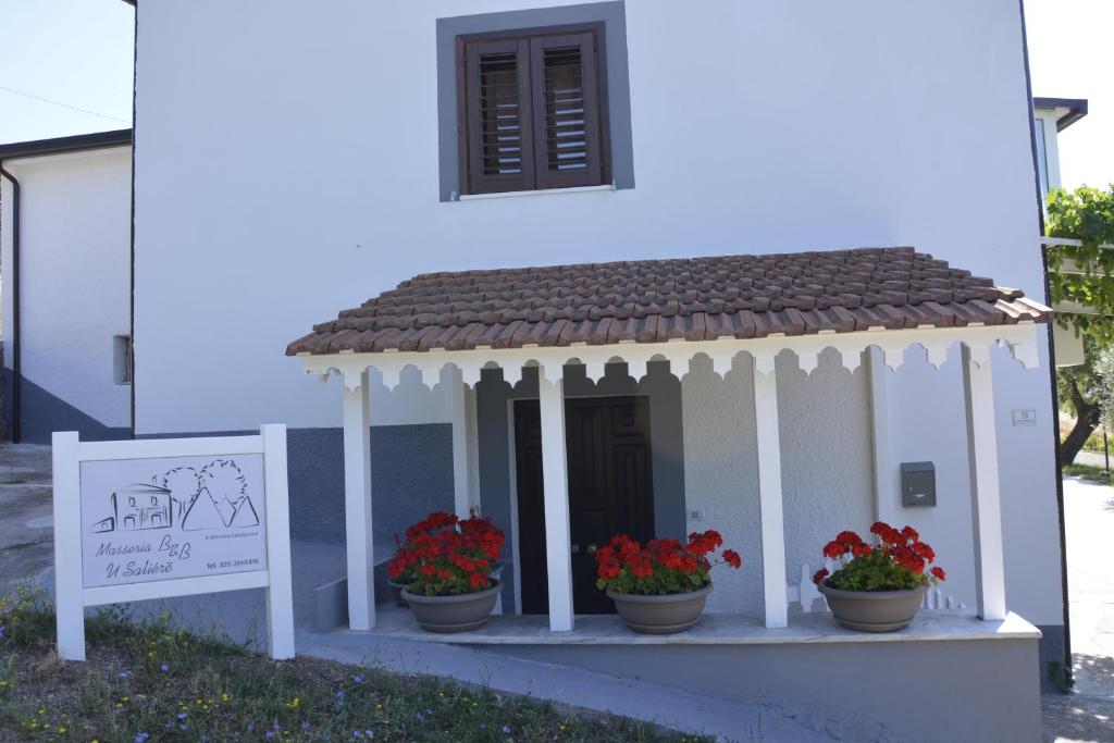 a small house with flower pots on a porch at B&B MASSERIA U Saliére in Sarconi