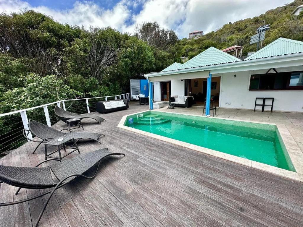 a deck with chairs and a swimming pool on a house at Modern Villa with Pool in Marigot - 100 m² in Marigot