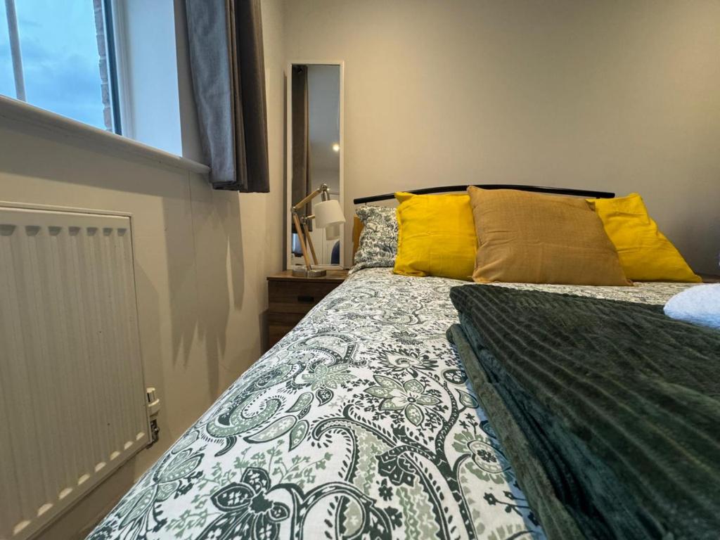 a bedroom with a large bed with yellow pillows at WBC Large Ensuite Room Wednesbury R2 in Bilston