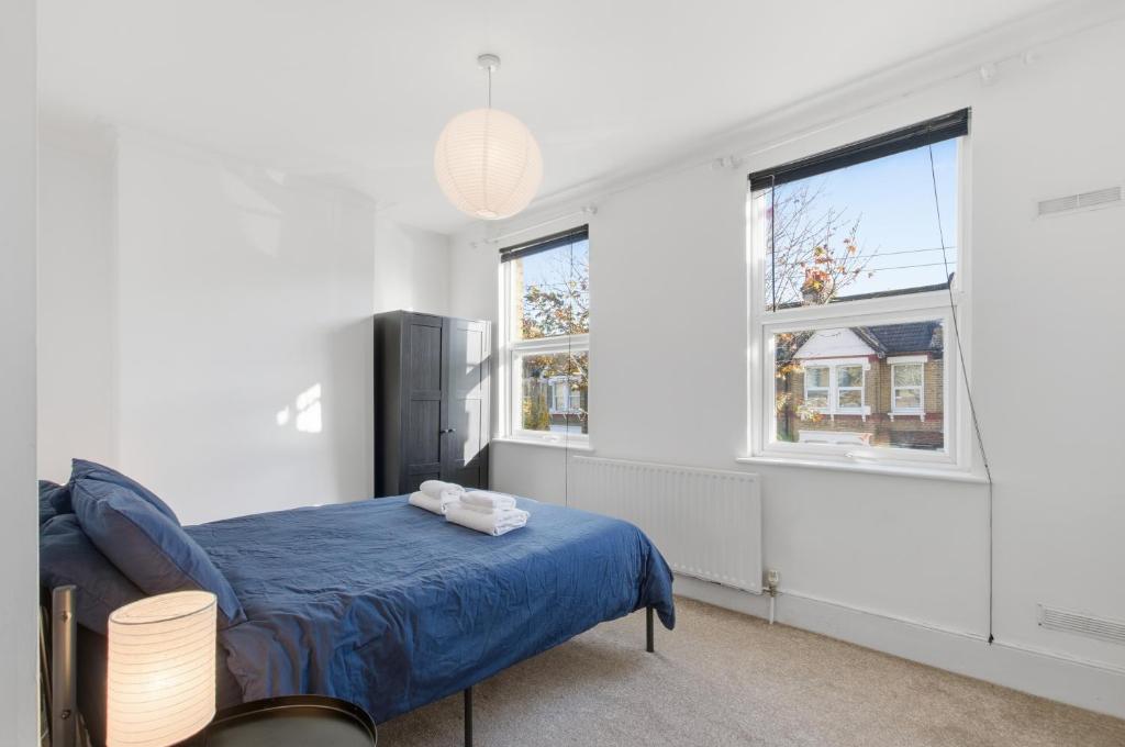 a bedroom with a blue bed and two windows at Comfy 3 bed Home in London in Elmers End