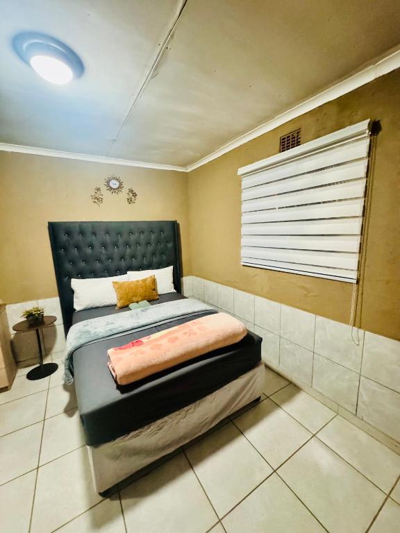 a bedroom with a bed and a window in it at Tseleng Guest House in Vosloorus