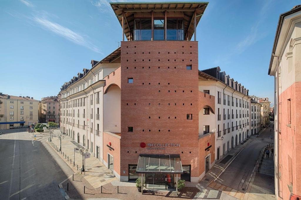 a building with a tower on the side of a street at NH Collection Torino Santo Stefano in Turin