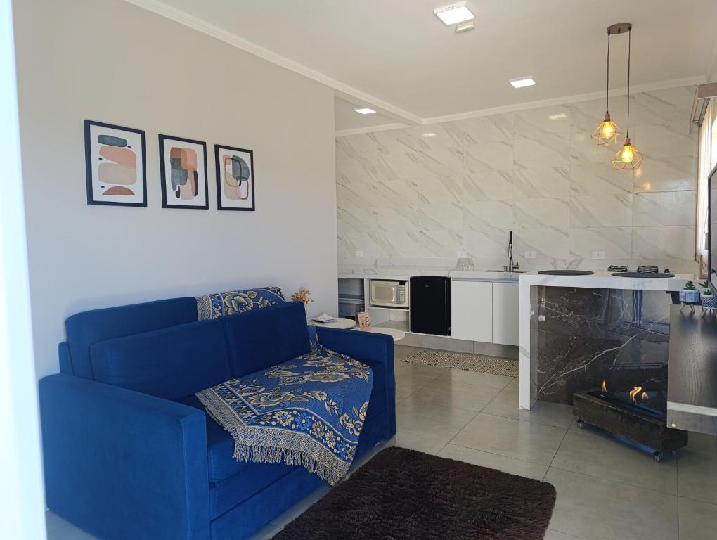 a living room with a blue couch and a kitchen at Apê Bella Vista Campos in Campos do Jordão