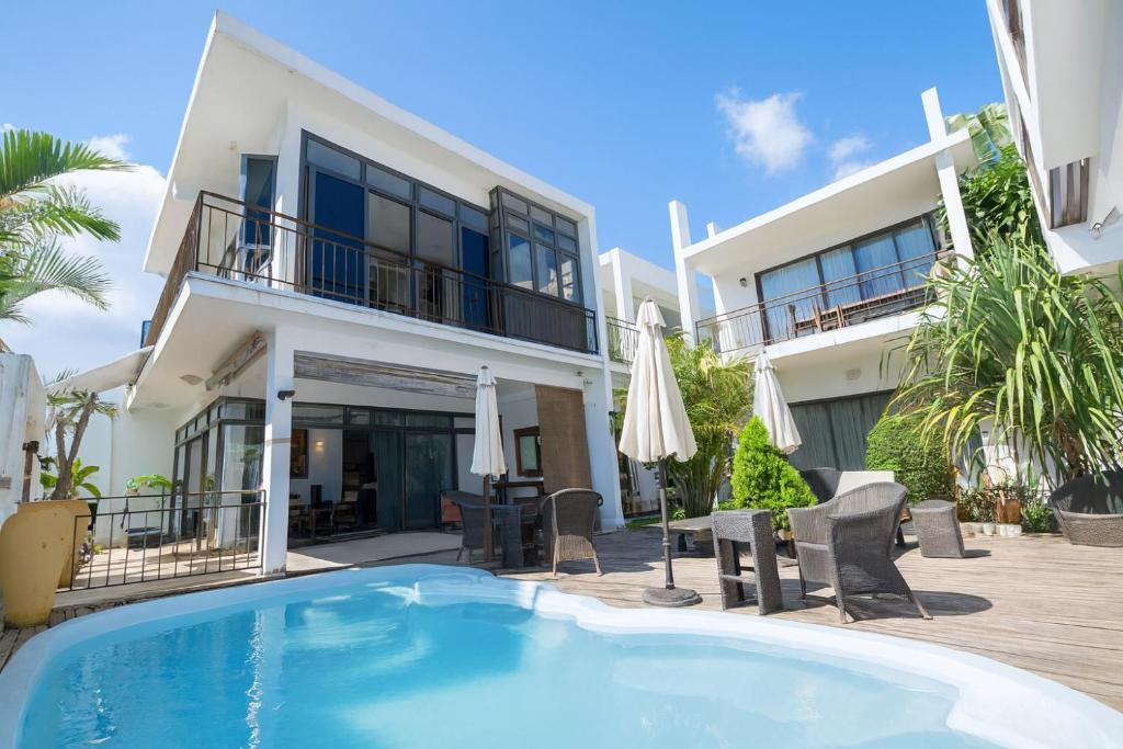 eine Villa mit einem Pool vor einem Gebäude in der Unterkunft Villa Alizée - Boutique Hôtel Expérience - Idéal Couples & Pros - Piscine - Restaurant - Rooftop bar - Parking privé - 10min Port-Louis - Ambiance Tropical chic & authentique in Port Louis