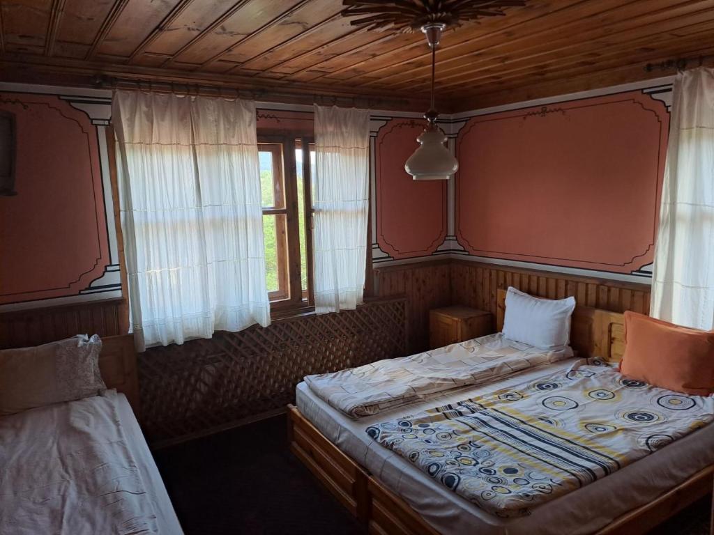 ein Schlafzimmer mit zwei Betten und zwei Fenstern in der Unterkunft Карагьозовата Къща in Kopriwschtiza