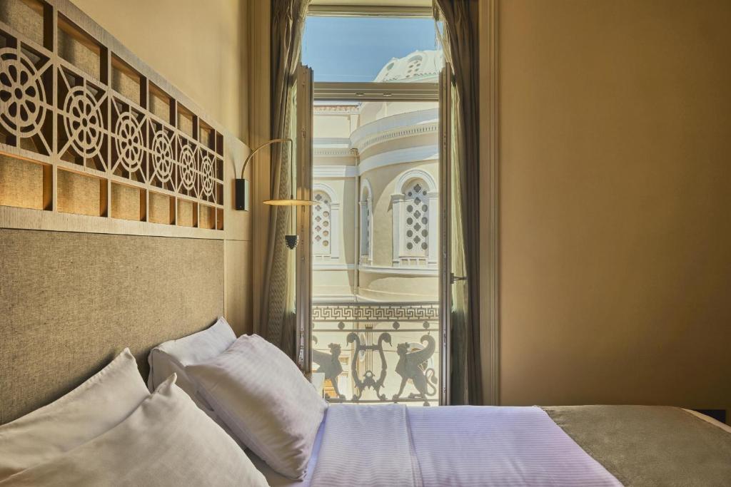 a bedroom with a bed and an open window at Athens 1890 Hotel & Spa in Athens