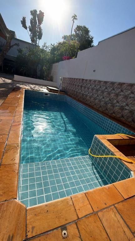 a swimming pool with blue tiles in a backyard at Chácara Barbosa in Rio Claro
