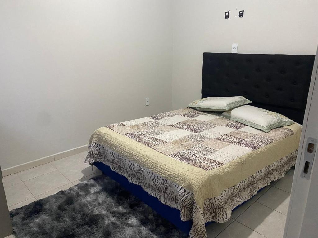 een slaapkamer met een bed met een dekbed en een tapijt bij AP completo a 5 min da Praia, Itapema-SC in Itapema