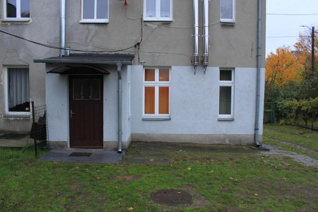 a white house with a door and a yard at Szczecin Prawobrzeże Apartament Zajazd in Szczecin