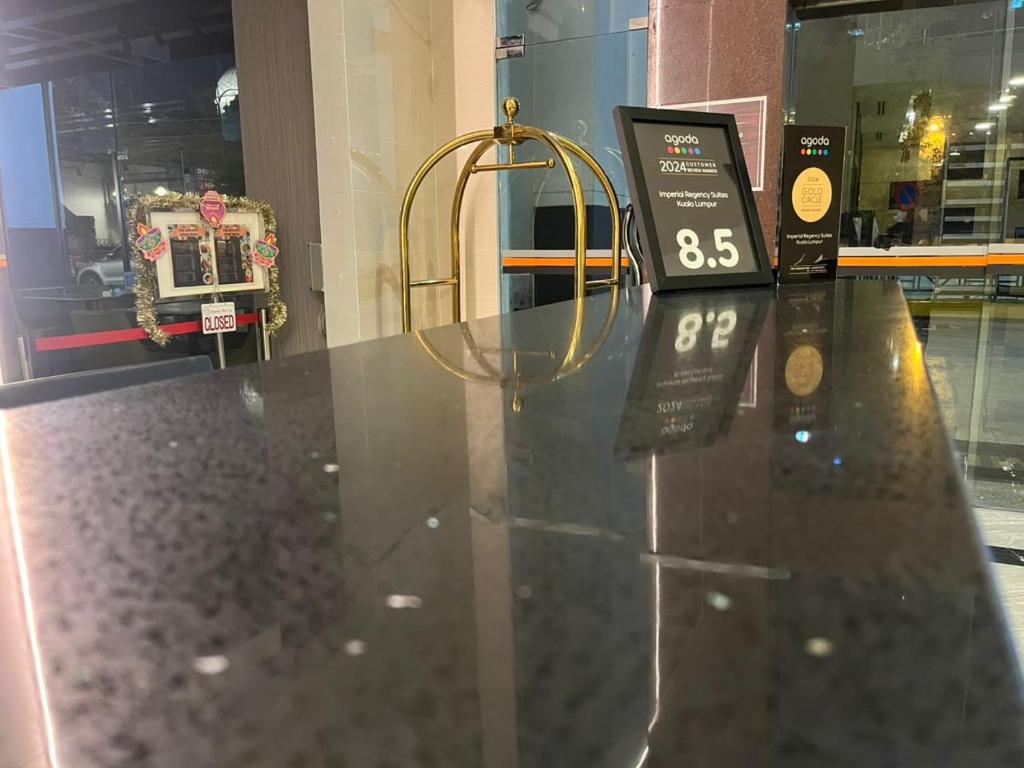 A polished front desk with a luggage trolley and a visible guest-rating display.