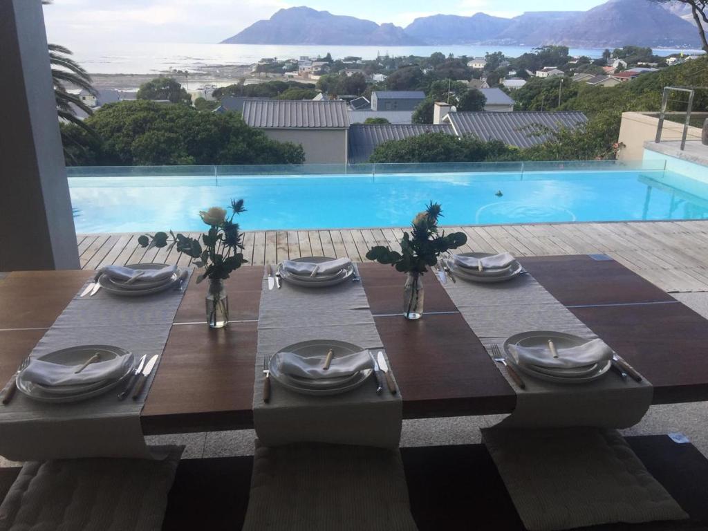 a table set up for a meal in front of a pool at Villa PheZulu in Kommetjie