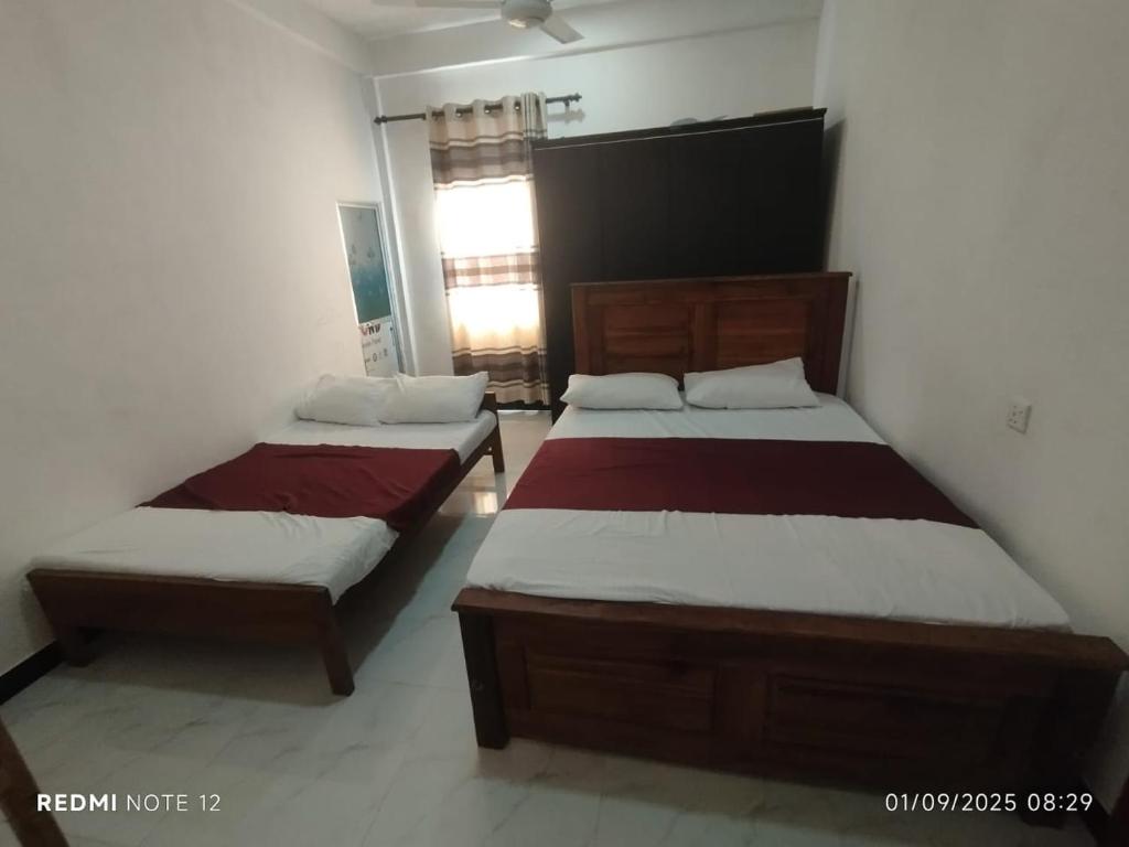 a bedroom with two beds and a window at Randuli Holiday Homes in Anuradhapura