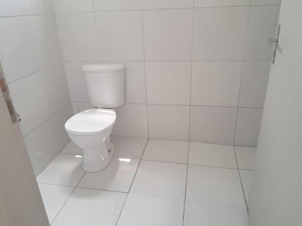 Camera con piastrelle bianche e bagno con servizi igienici. di Meu aconchego a Belém