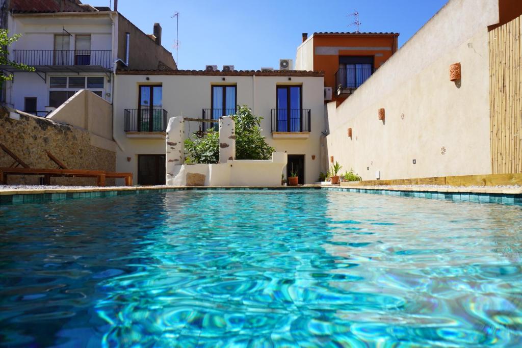 a swimming pool with blue water in front of buildings at Ses Terrisses Hotel in Palafrugell