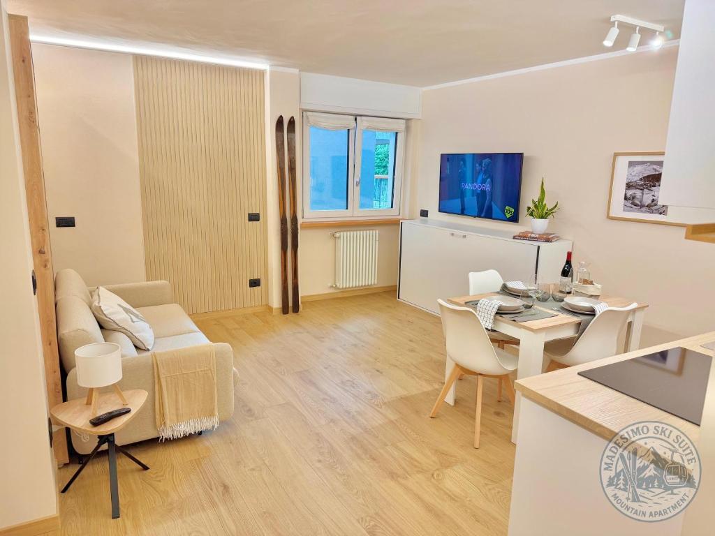 ein Wohnzimmer mit einer Couch und einem Tisch mit Stühlen in der Unterkunft Madesimo Ski Suite in Madesimo
