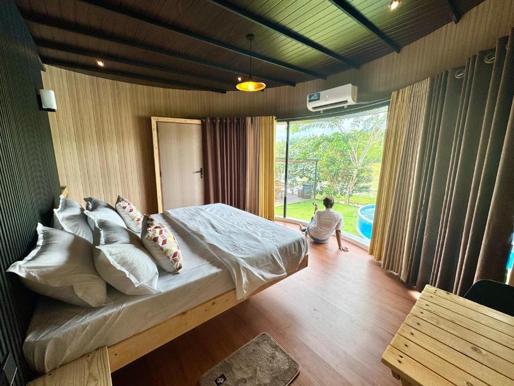 a person sitting on a bed in a room with a window at The Glamp - Homagama in Talagala