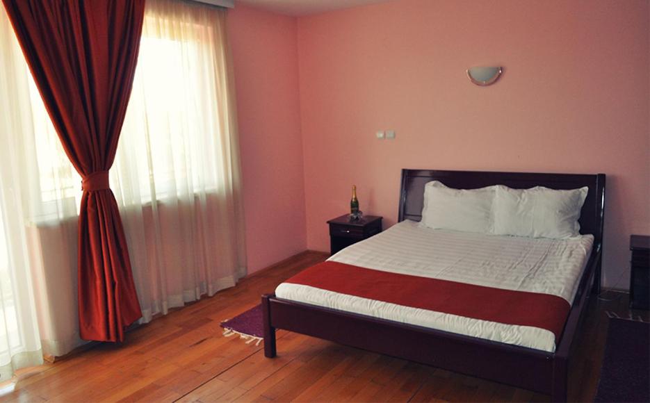 Hotel Satelit Kumanovo في كومانوفو: غرفة نوم بسرير ونافذة مع ستائر