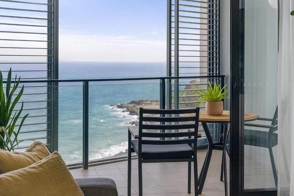 a balcony with a table and chairs and the ocean at 803 - Stylish Retreat - Ocean Views & Parking in Newcastle