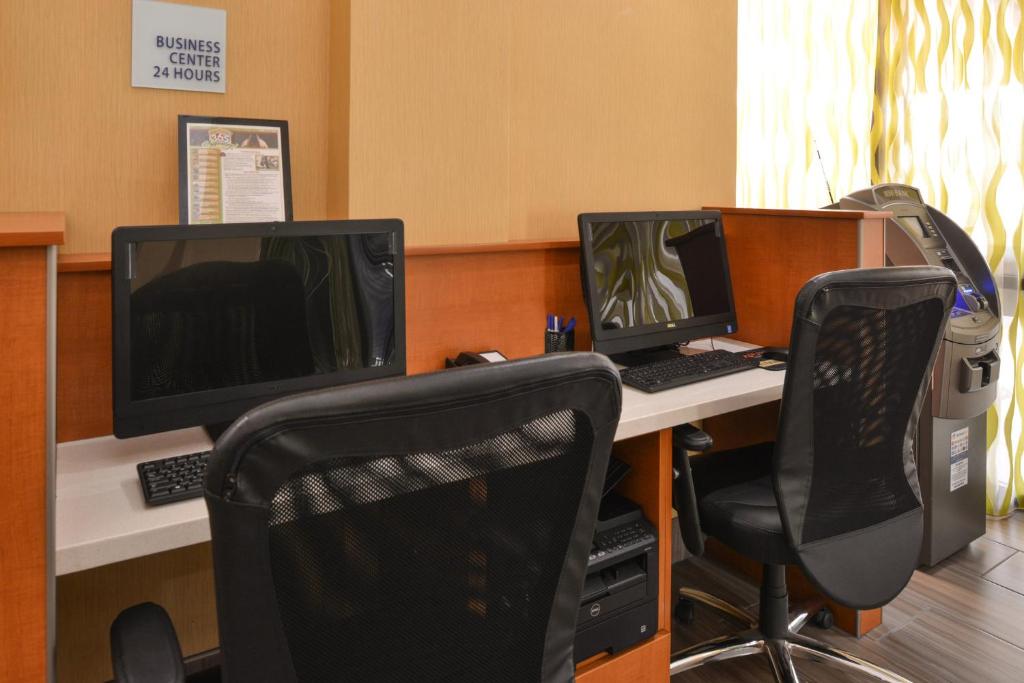 dois monitores de computador numa secretária com duas cadeiras em Holiday Inn Express Flagstaff by IHG em Flagstaff
