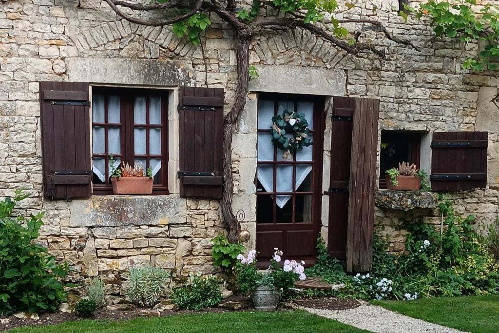 a stone building with windows and flowers in the yard at Romantic Cottage Retreat for Two in South Vienne in Champniers