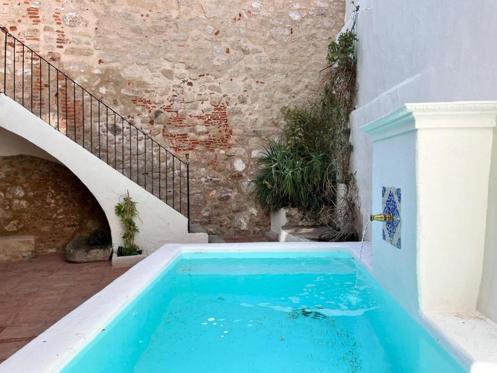 a blue swimming pool next to a building at Casa de Solís in Trujillo