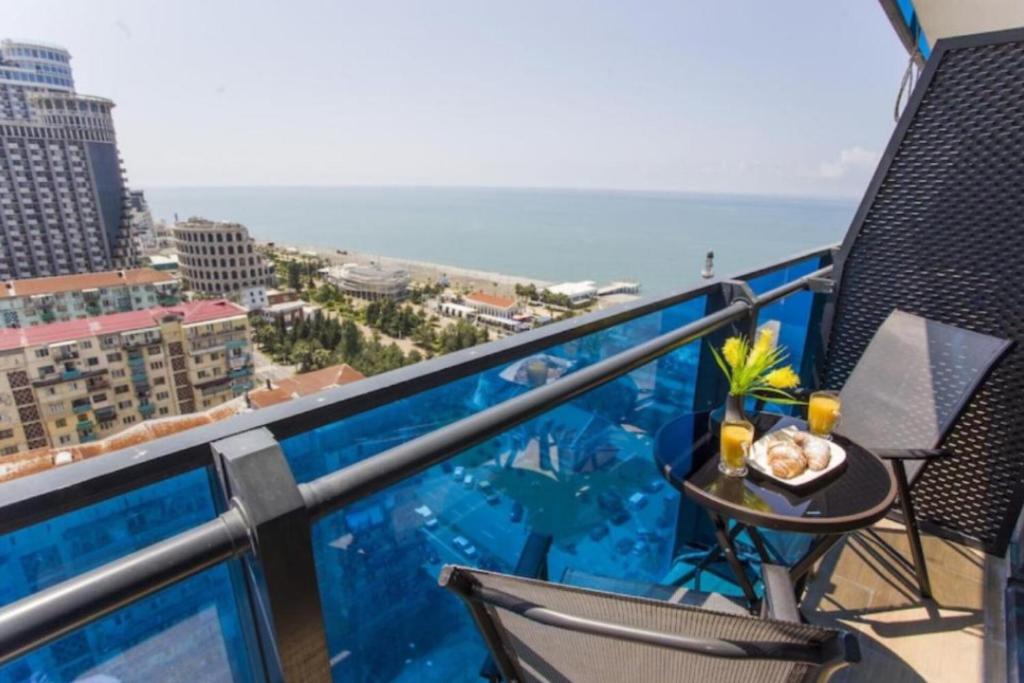 a balcony with a table and chairs and the ocean at Deluxe Aparthotel In Orbi City in Batumi