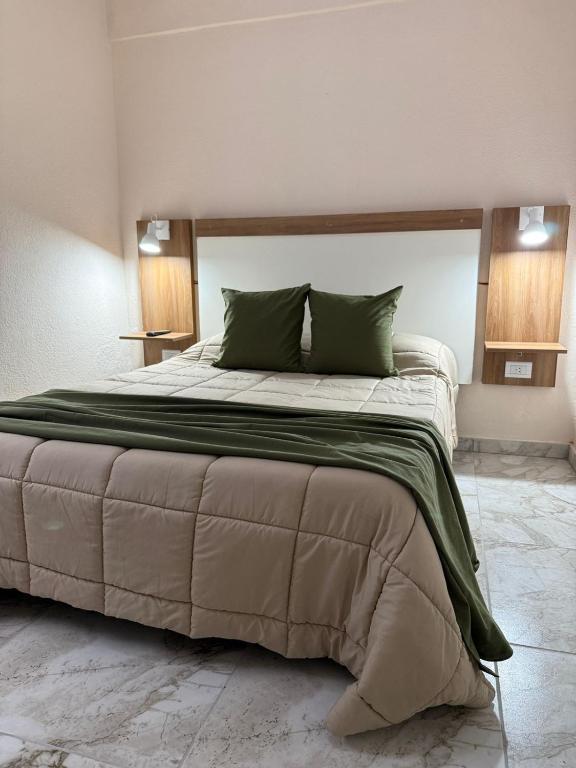 a large bed with green pillows in a bedroom at Continente Park in San Clemente del Tuyú
