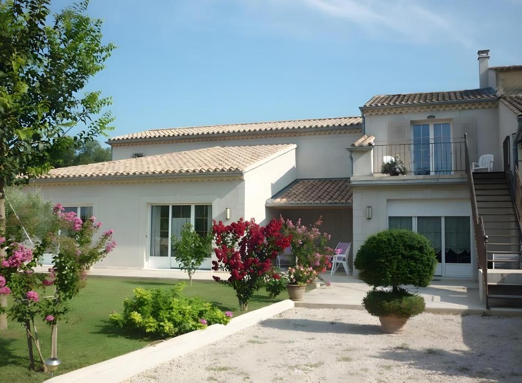 una gran casa blanca con flores en un patio en La Bastide Des Mereuilles, en Caderousse
