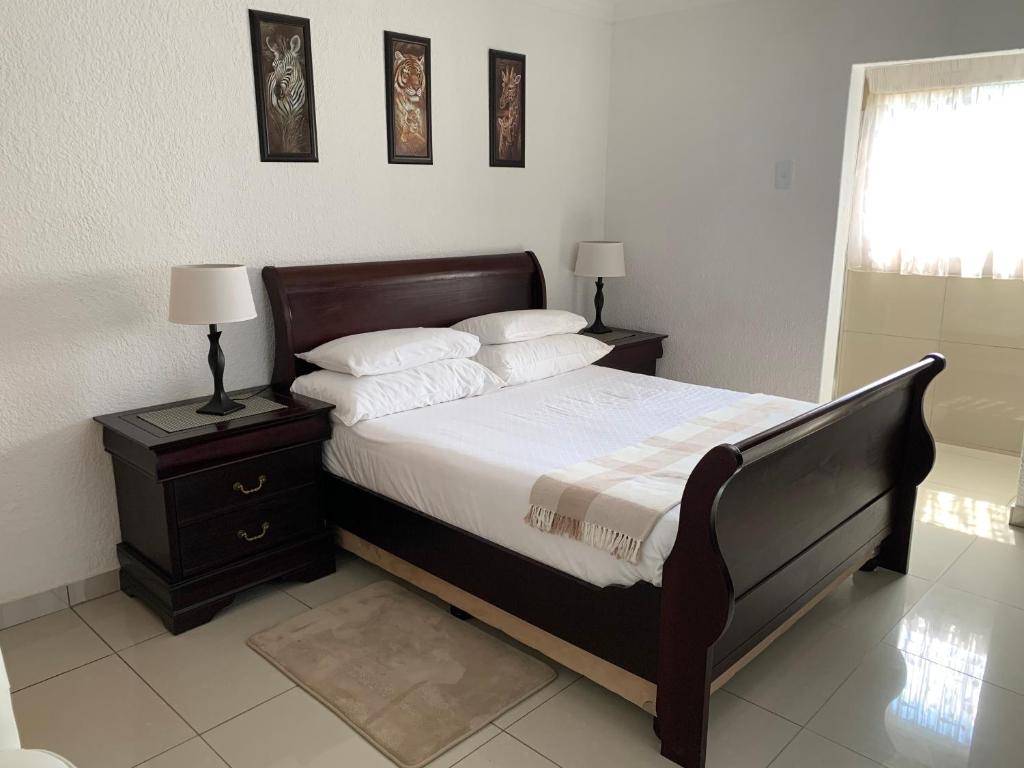 a bedroom with a bed and a nightstand with two lamps at Xintu Xa Hina Guesthouse in Nkowakowa