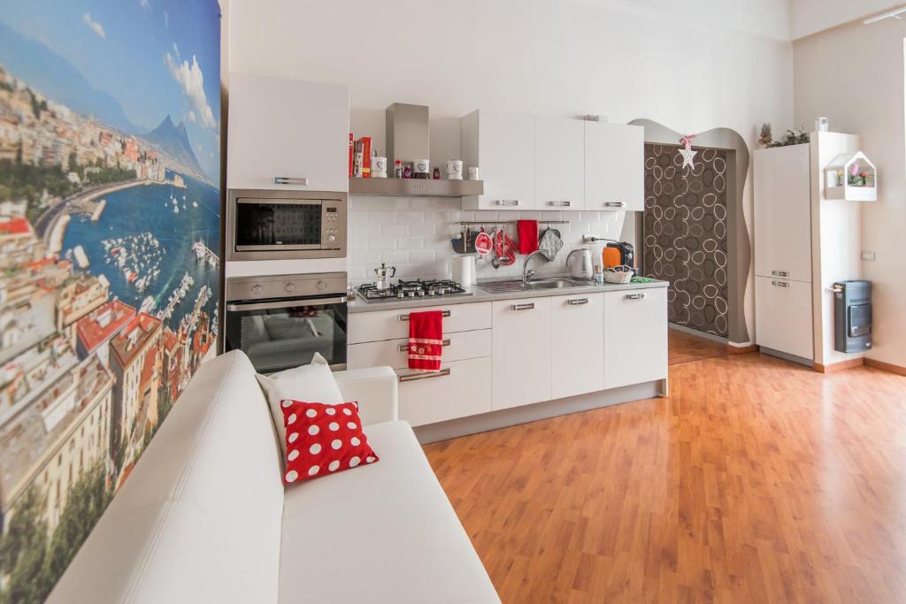 ナポリにあるラ カルトリーナ ディ ナポリの白いキャビネットとソファ付きのキッチンが備わります。