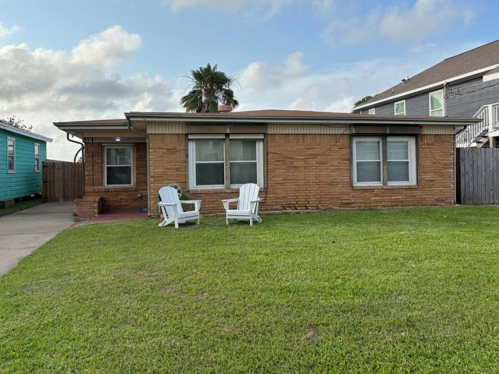 a house with two chairs and a table in the yard at Paradise Surf House in Galveston