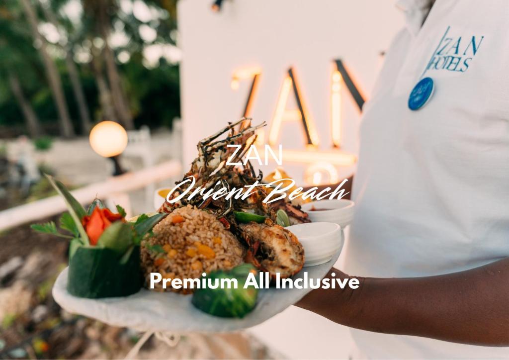 a person is holding a plate of food at ZAN Orient Beach Hotel in Bwejuu