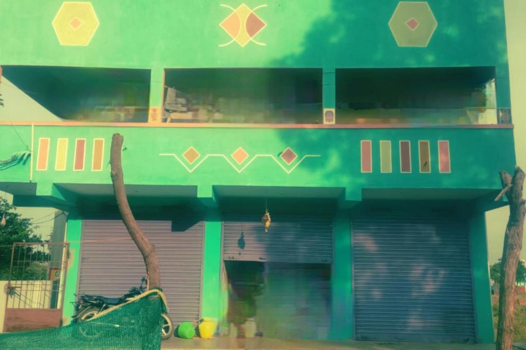 Ramana Maharshi Guest Houses في تيروفانمالي: مبنى اخضر مع شرفة وجراج