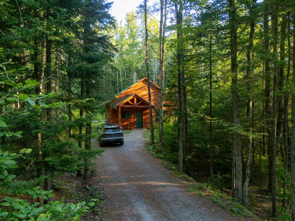 a car parked in front of a log cabin in the woods at Robert Frost Mountain Cabins in Middlebury