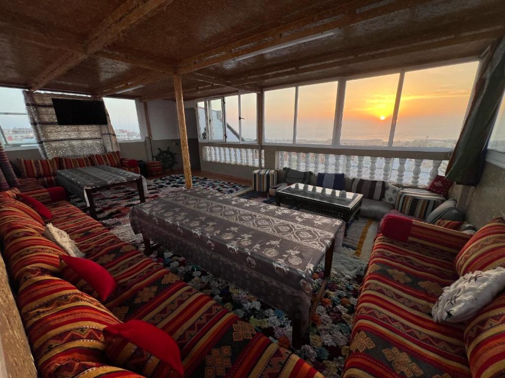 a room with couches and a balcony with a sunset at Surf capitain in Tamraght Ouzdar