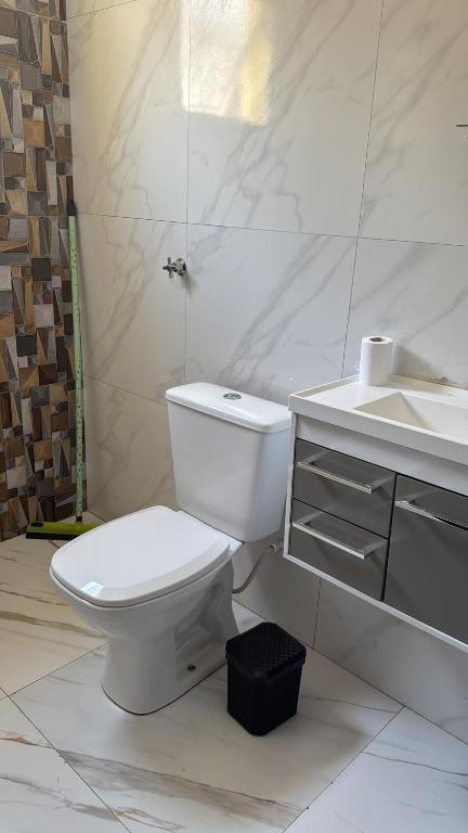 a white bathroom with a toilet and a sink at Recanto das Onças in Extrema