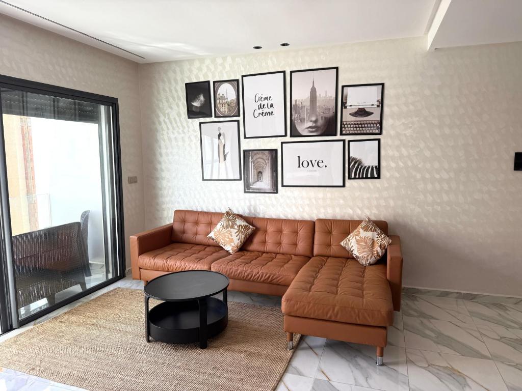 a living room with a couch and pictures on the wall at bel appartement à centre Mahdia plage 2 in Kenitra