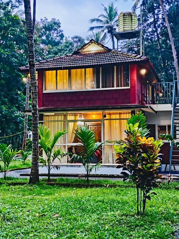 a house with palm trees in front of it at Homestay Rooms Muzhakkunnu Near Kannur International Airport in Iritti