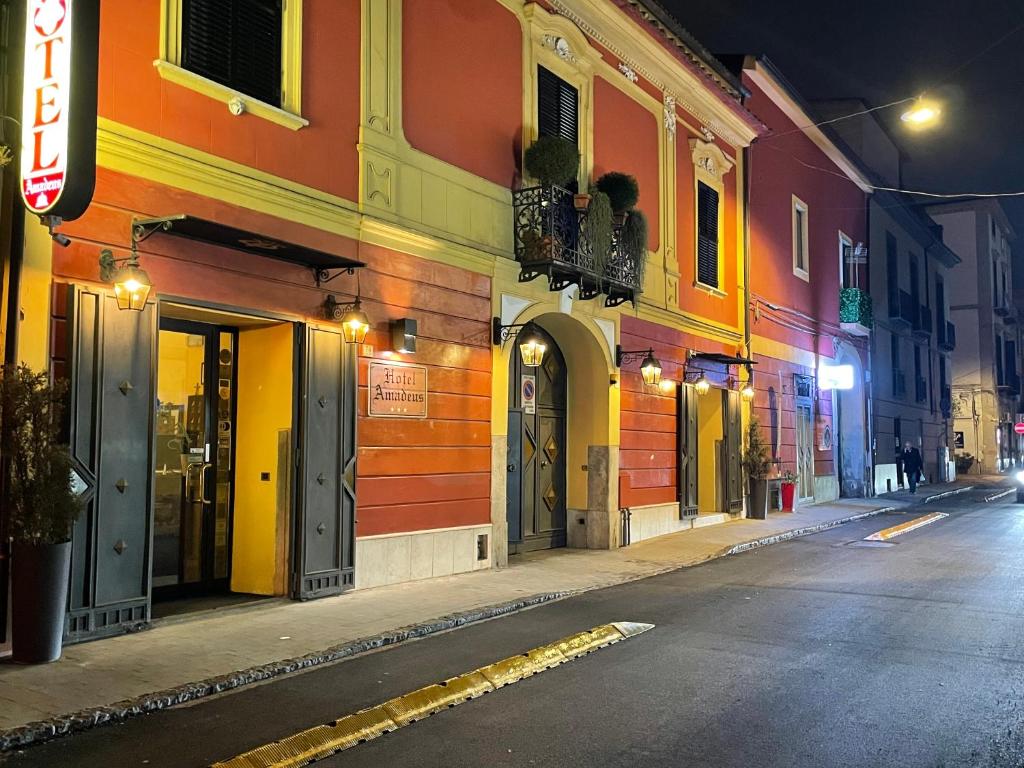 an empty city street at night with colorful buildings at Hotel Amadeus in Caserta