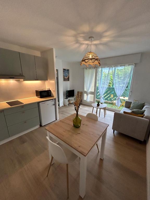 a living room with a table and a kitchen at Le Belvédère - Balcon plein sud au calme in Saint-Pierre-du-Mont