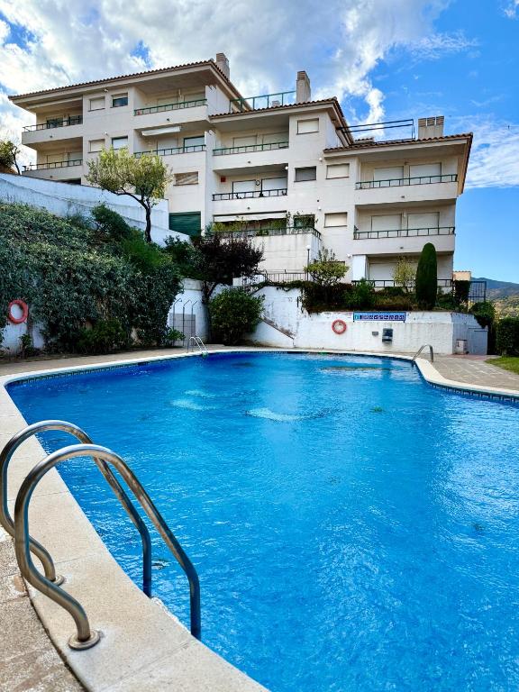a large blue swimming pool in front of a building at Apartamento 1 con Piscina en Llança in Llança
