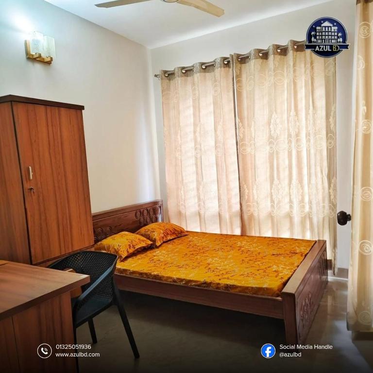 a bedroom with a bed and a chair and a window at Azul BD in Bāiljuri