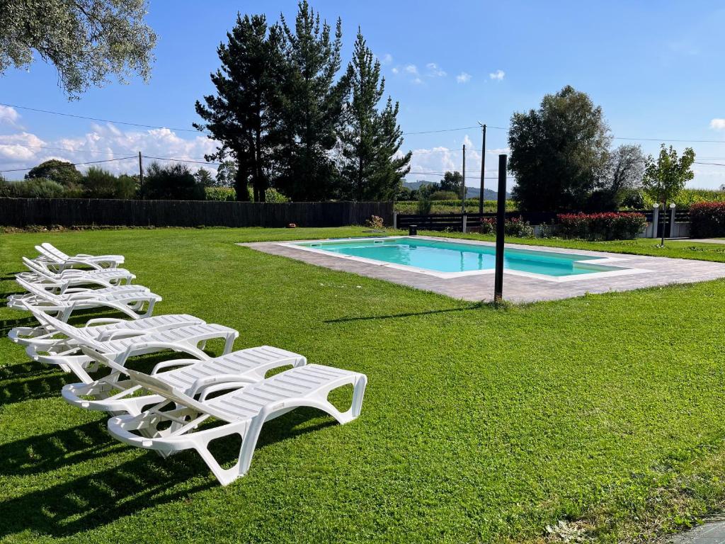 a row of white lounge chairs next to a swimming pool at Casa O Real in Boimorto