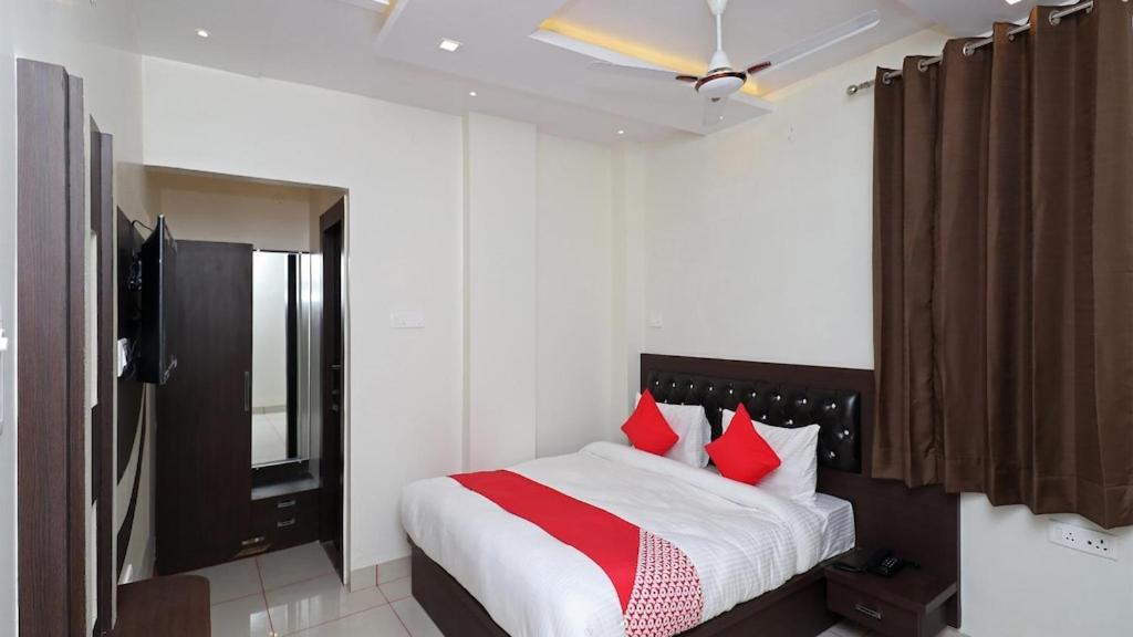 a bedroom with a bed with red pillows and a television at Hotel Darshan Inn in Prayagraj