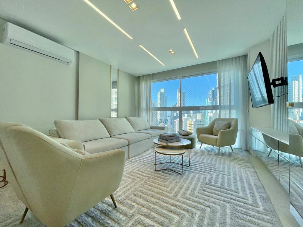 a living room with a couch and chairs and a tv at Phoenix Tower FG - Lazer Resort a Passos do Mar BC in Balneário Camboriú