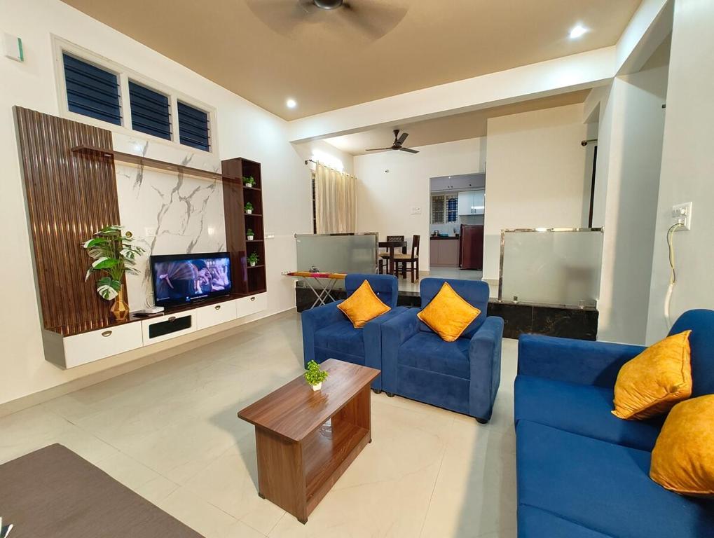 ein Wohnzimmer mit zwei blauen Sofas und einem Fernseher in der Unterkunft Namasvi 2Bedroom AC House in Narasimharaja Puram