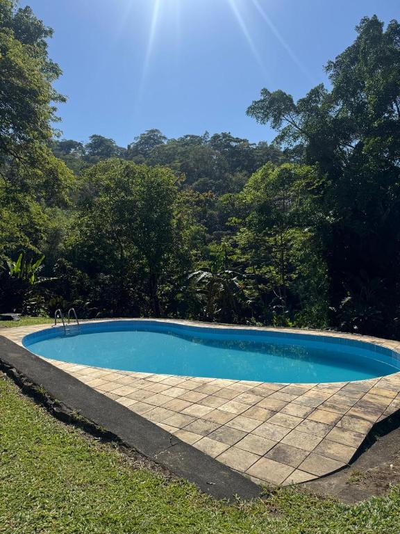 a blue swimming pool in the grass with trees at Recanto do Bosque in Majé