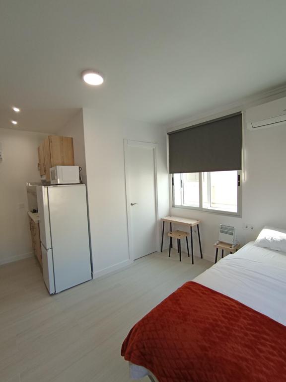 a bedroom with a bed and a refrigerator and a table at Estudios Diego in Puerto de Sagunto