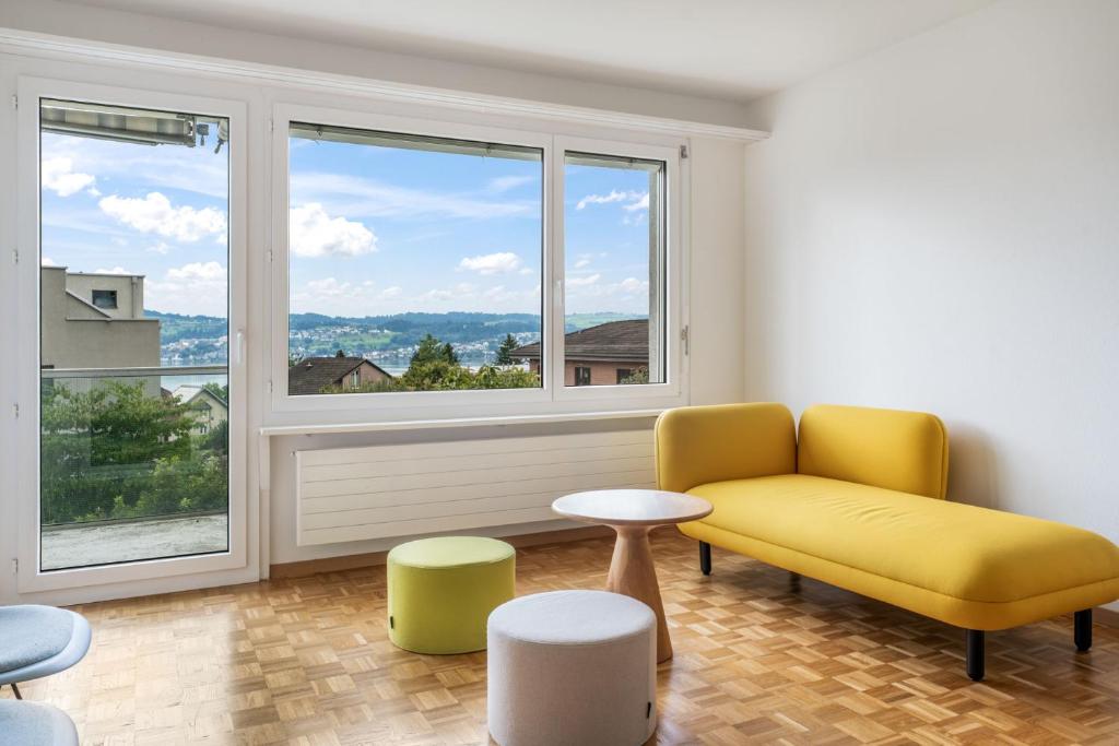 a living room with a yellow couch and a window at EXQUIS Design 3-Room Apartment KNOLL I Zurich Lake View I Balcony I Family-Friendly in Männedorf