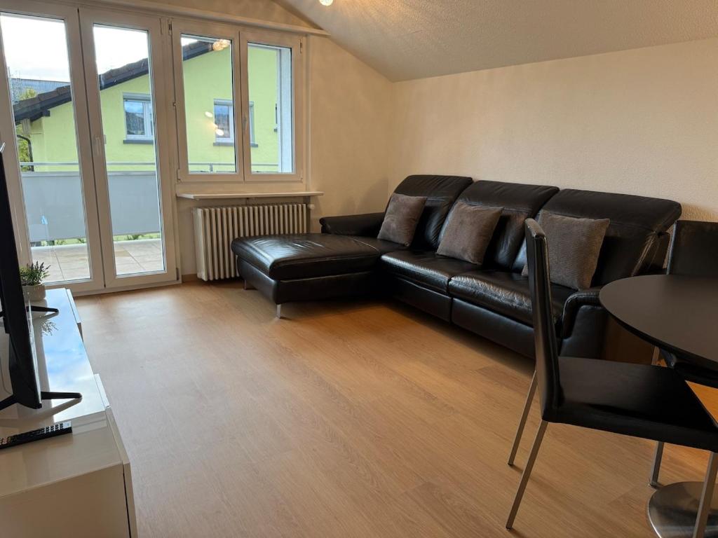 a living room with a black leather couch and a table at Swiss Suites Oberentfelden in Oberentfelden